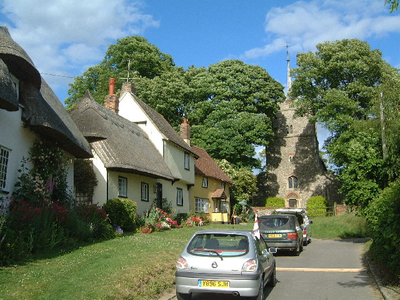 A road leading to a Church in Wendens Ambo, with thatched cottages on the left.